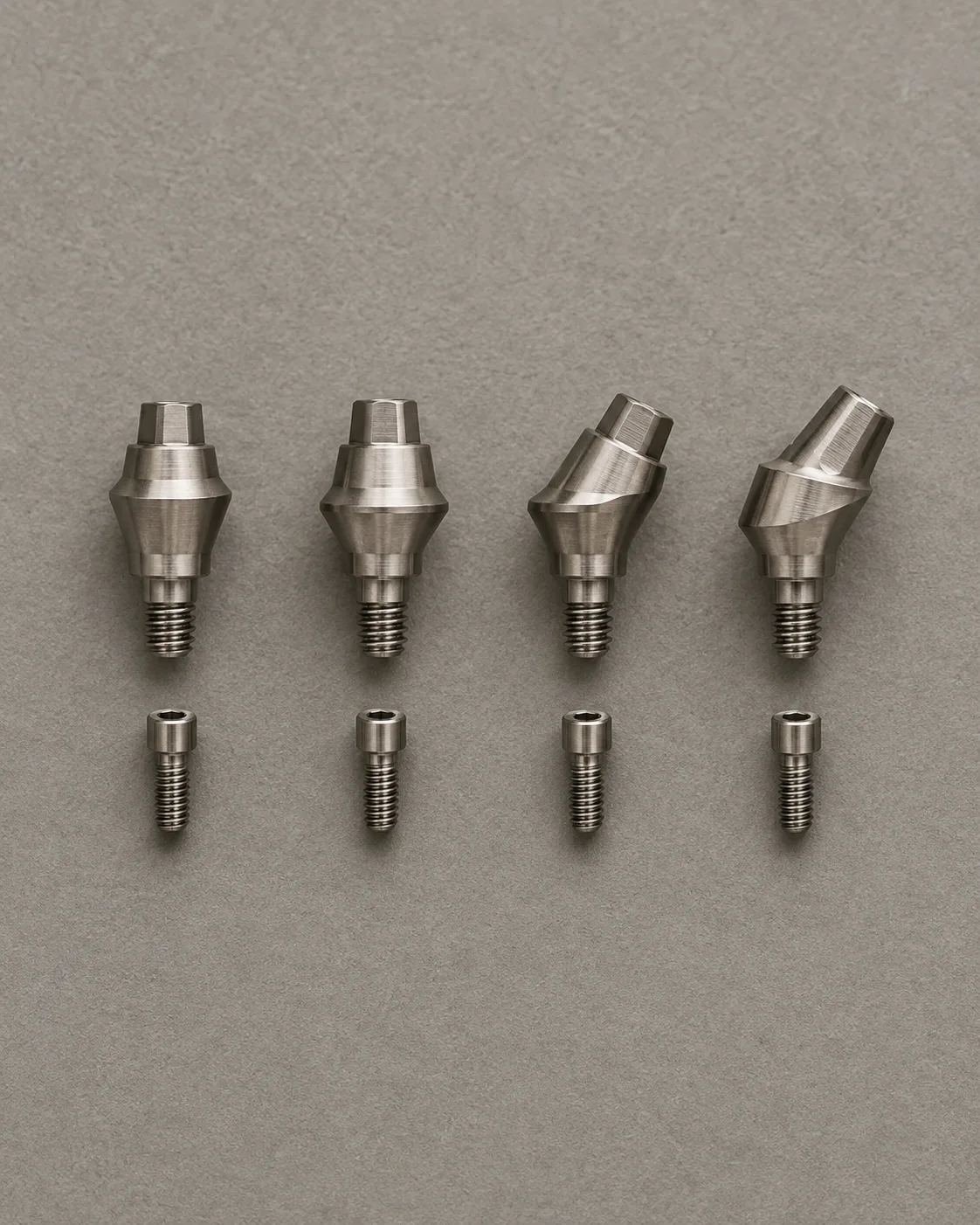Four titanium multi-unit abutments, two straight and two angled, with their screws laid beneath