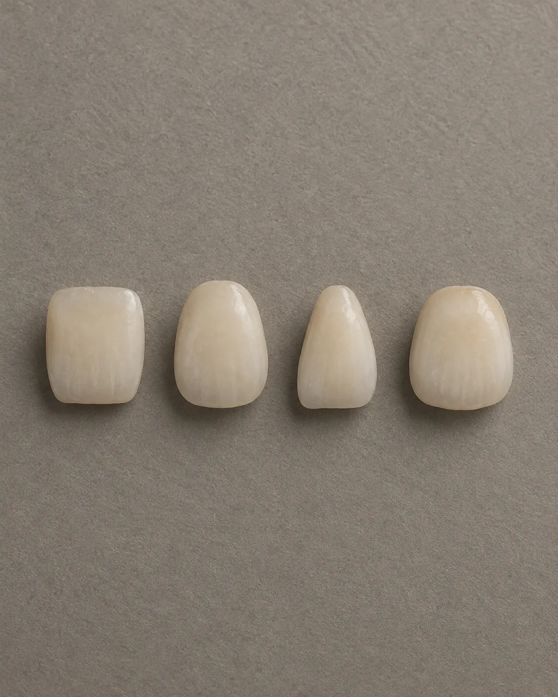Four porcelain front teeth in a row, one square, one ovoid, one tapered and one rounded